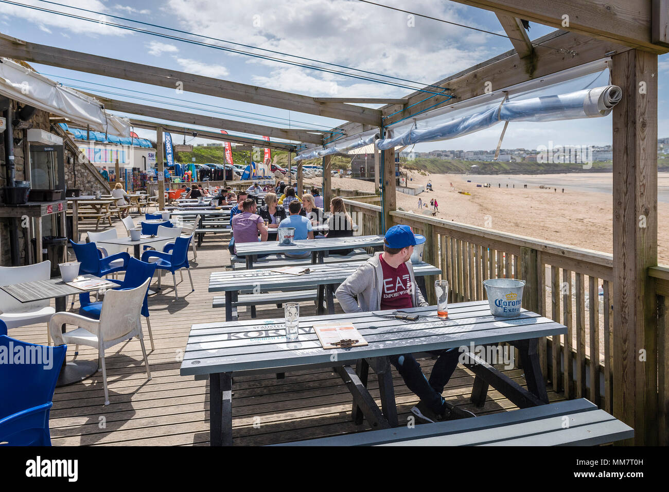 Los turistas relajarse en la terraza del bar de la playa Fistral con vistas a la playa Fistral en Newquay, Cornwall. Foto de stock