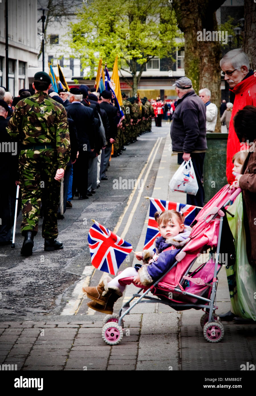 Una niña mira descontentos del ejército durante un desfile a través del centro de la ciudad de Gloucester Foto de stock