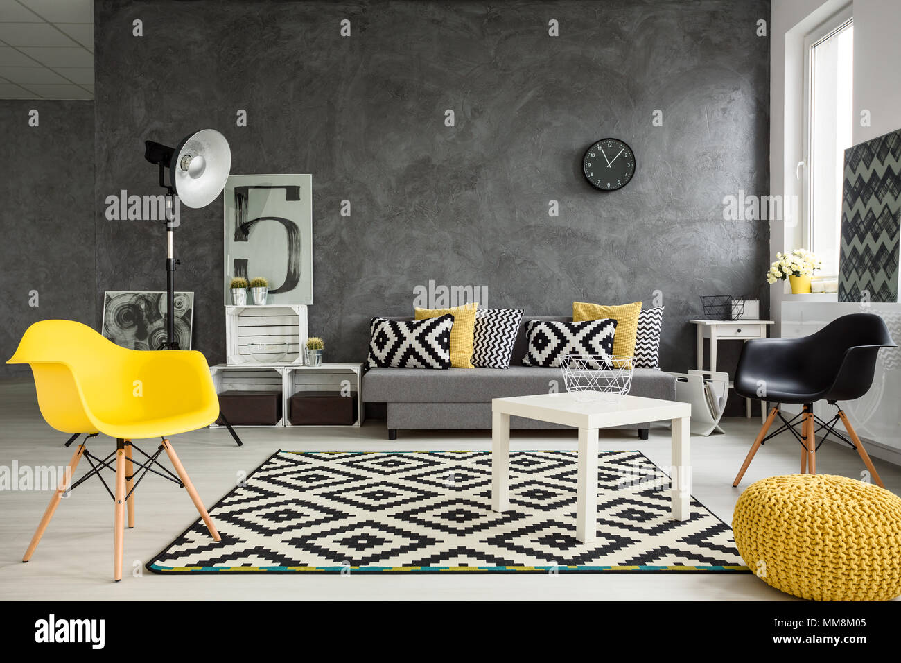 Gris sala de estar con sofá, sillas, una lámpara de pie, una pequeña mesa,  detalles en amarillo y el patrón de decoración en blanco y negro Fotografía  de stock - Alamy