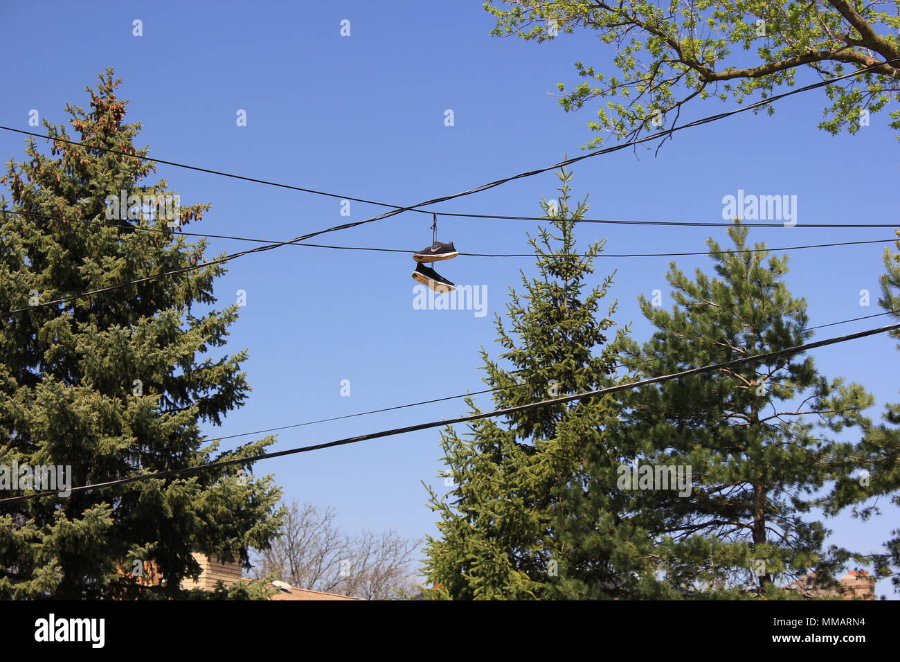 Par de Nike negro colgando de los cables eléctricos spanning sobrecarga a través de una calle, generalmente una señal de una droga casa cercana Fotografía de stock - Alamy