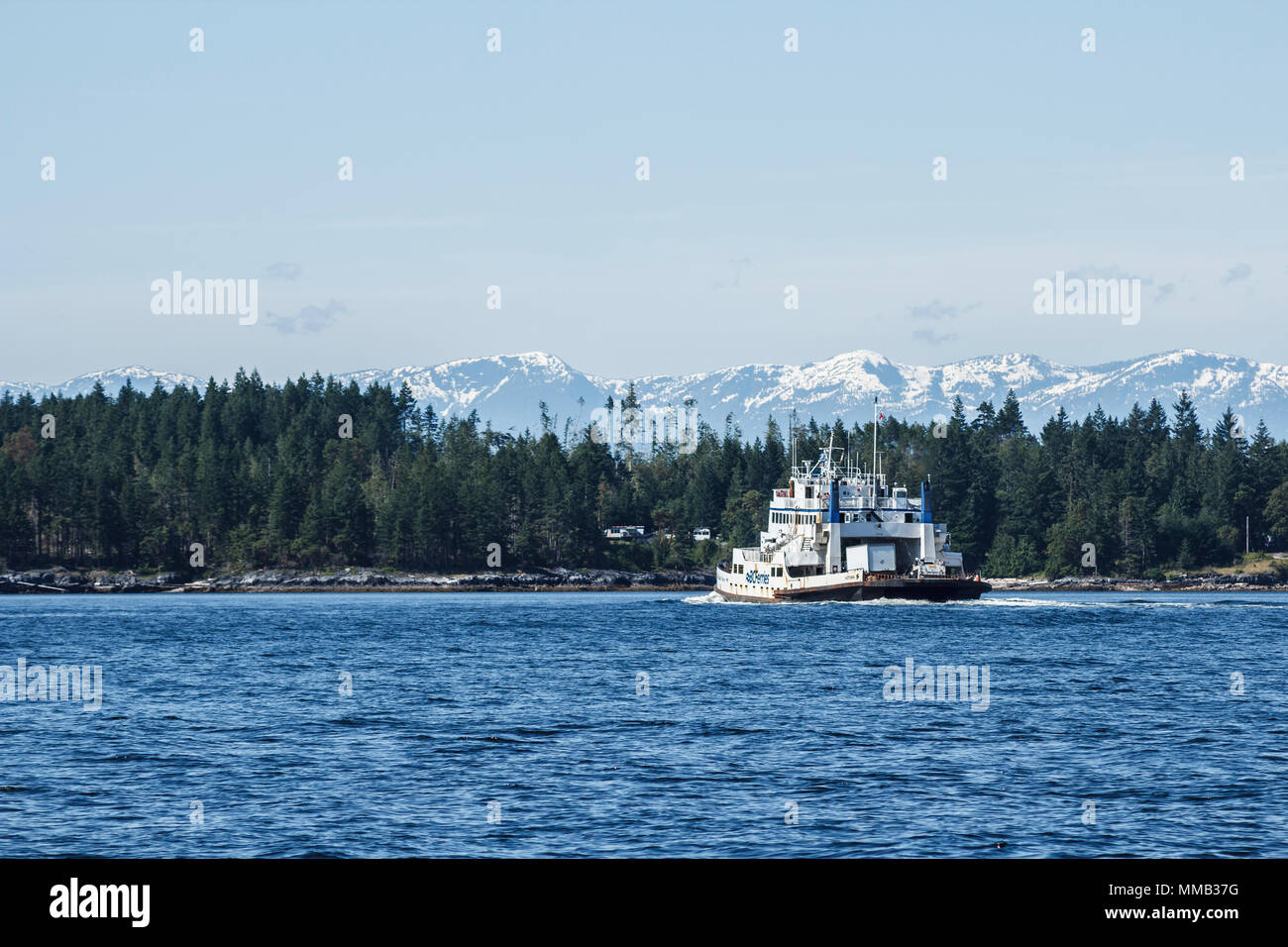 En un brillante día de verano, el buque "BC Ferries North Island Princess' se aproxima a la isla Texada, con los picos nevados de rango más allá de la costa. Foto de stock