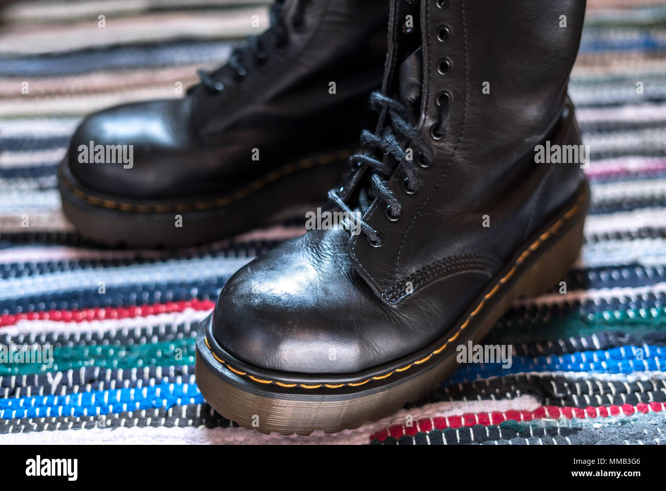 Close-up de dos robustas, tobillo botas de cuero negro sobre una alfombra colorida Foto de stock