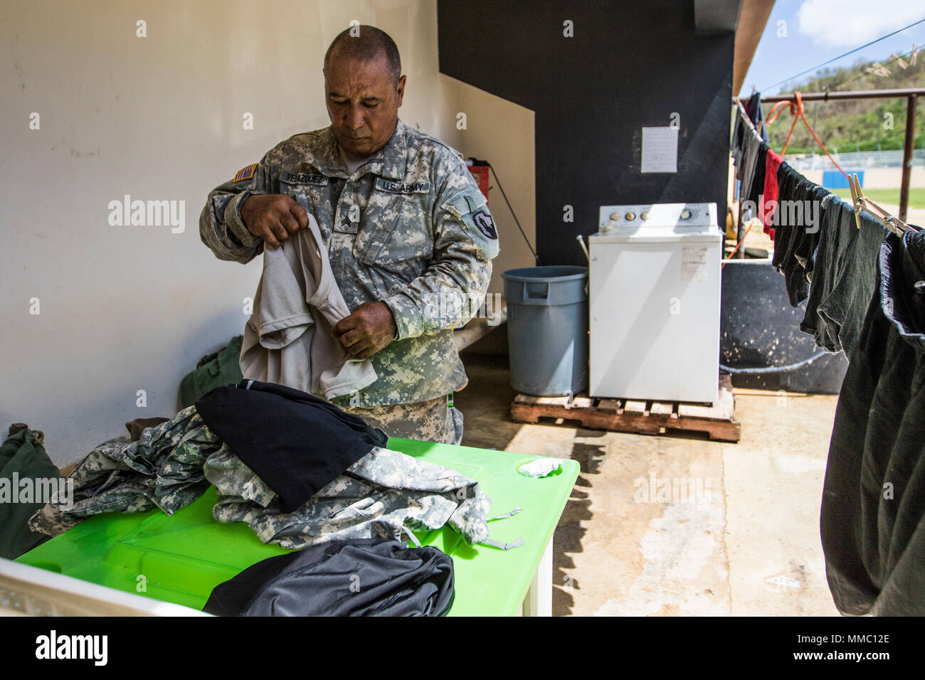 El sargento de la Reserva del Ejército de Estados Unidos. Roberto Velázquez  dobla la ropa en el banquillo del estadio local en Yauco, Puerto Rico, 7 de  octubre, 2017. Velázquez donó su