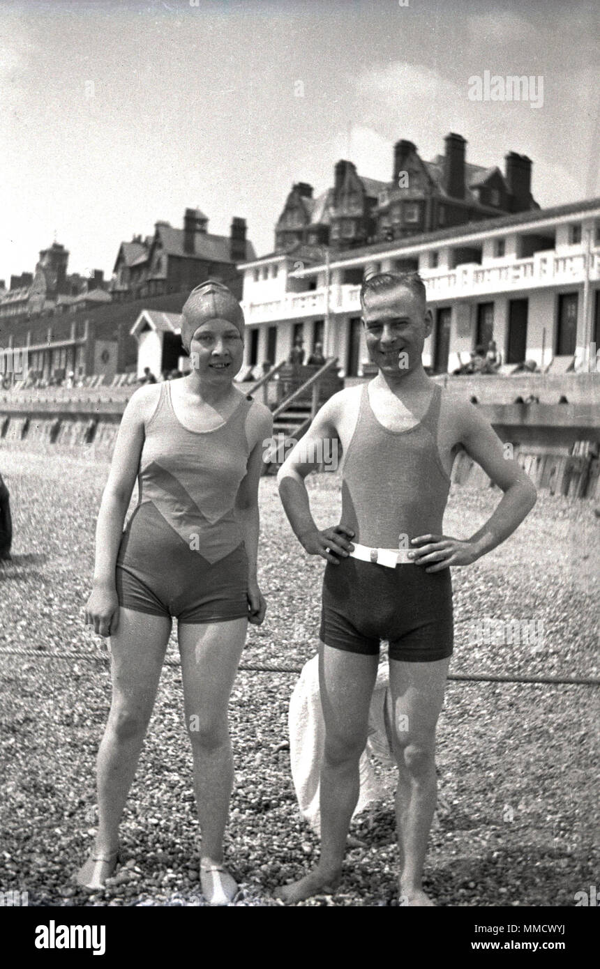 1930, un hombre y una mujer en traje de baño del día de pie junto a una  playa de guijarros en el paseo marítimo, Inglaterra, Reino Unido Fotografía  de stock - Alamy