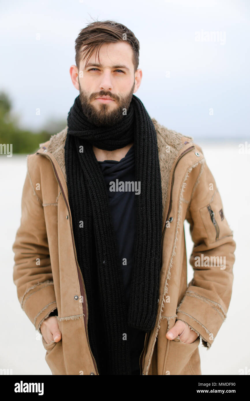 Retrato del hombre europeo joven con llevar abrigo y bufanda negra en permanente fondo en invierno Fotografía de - Alamy