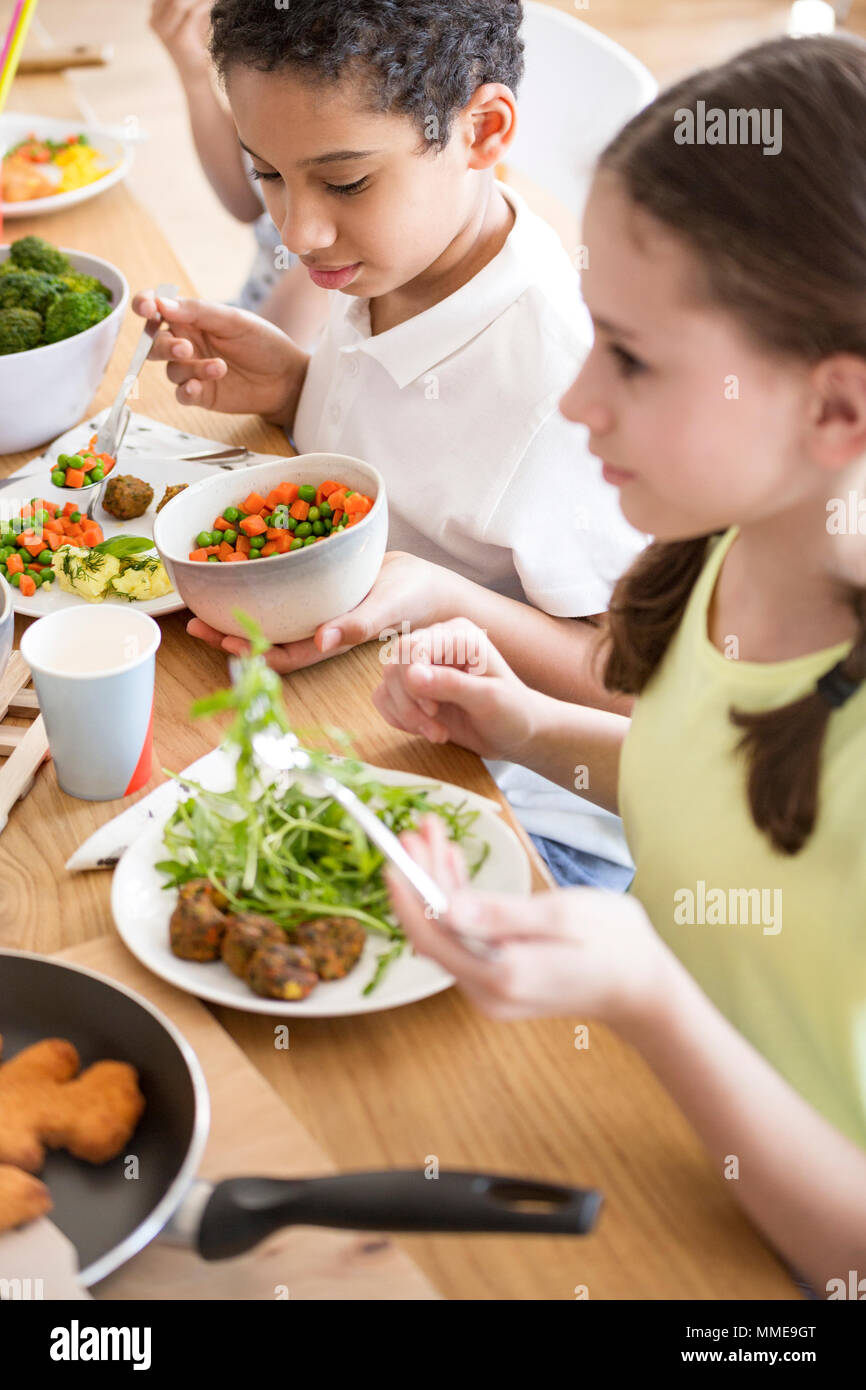 Ángulo alto de niños comer verduras para la cena en la escuela Foto de stock