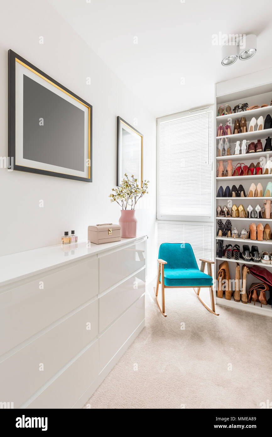 Elegante blanco walk-in closet con zapatos organizados en estanterías,  persianas, aparador, Sillón azul y rosado pastel detalles Fotografía de  stock - Alamy