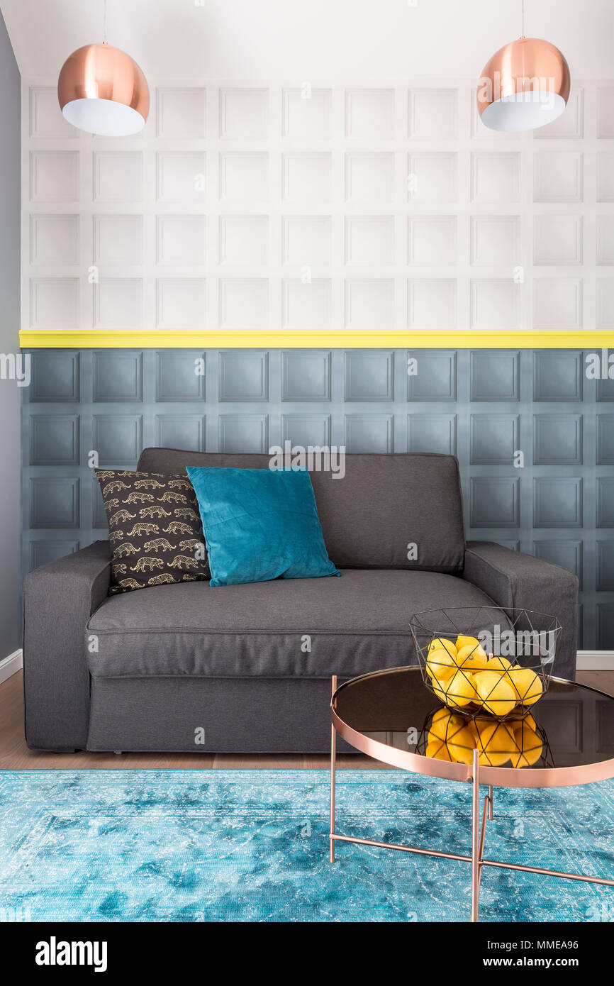 Salón interior en estilo elegante con el cobre, mesa de café, lámparas  decorativas y cojines en azul y negro acogedor sofá gris Fotografía de  stock - Alamy