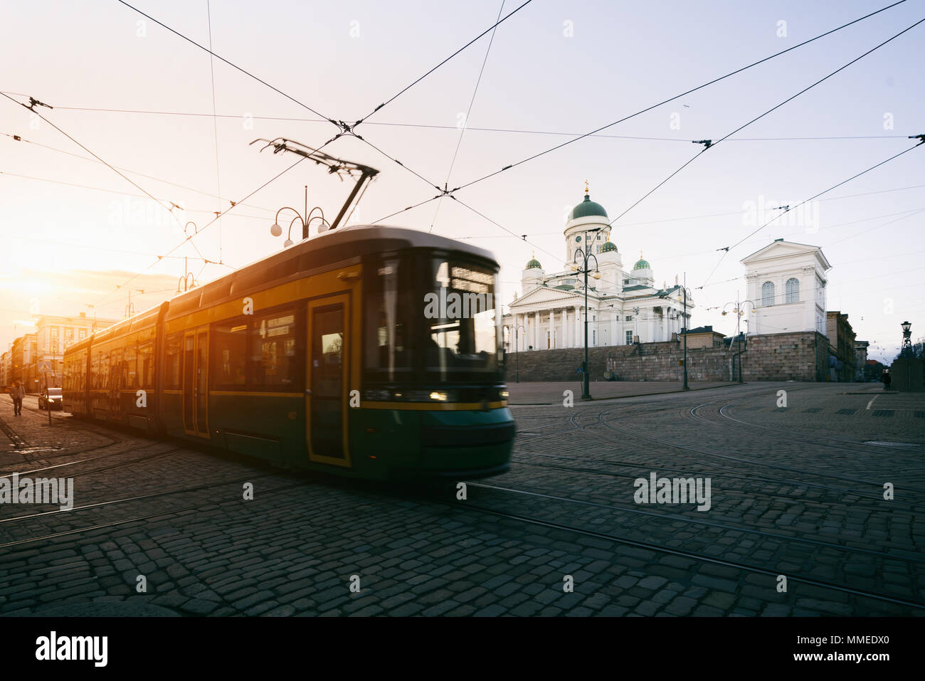 Tranvía pasando la Plaza del Senado de Helsinki durante la puesta de sol con la Catedral de Helsinki en el fondo en Finlandia. Foto de stock