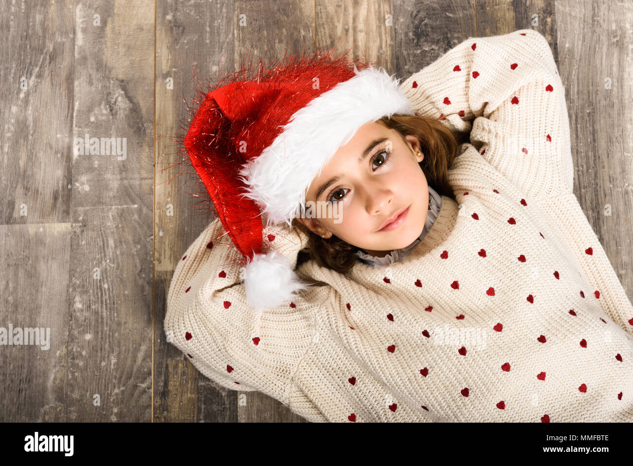 Adorable niña vestidos de santa hat acostado en el piso de madera. La ropa  de invierno para Navidad Fotografía de stock - Alamy