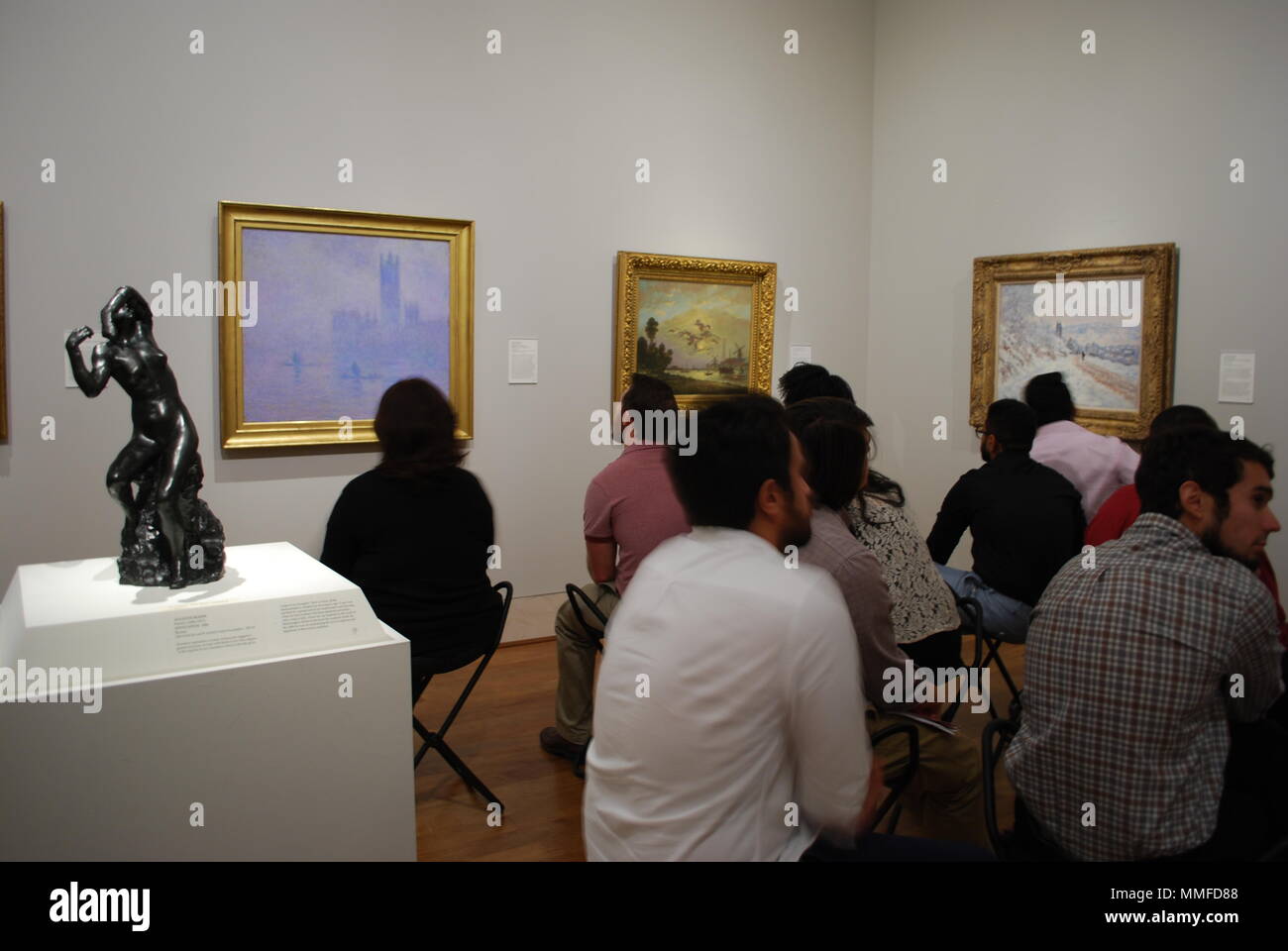 Grupo de adultos en el museo de arte. Gente sentada mirando en una famosa pintura artística. Grupo multirracial de la población de estudio. La curiosidad, el concepto de la educación. Foto de stock