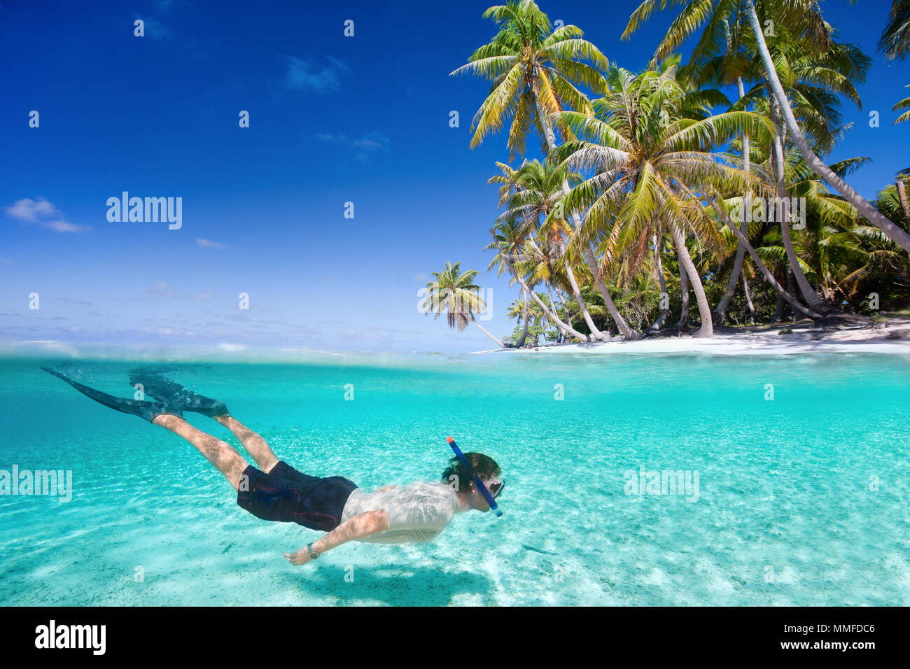 Hombre nadando en aguas claras tropicales delante de exótica isla Foto de stock