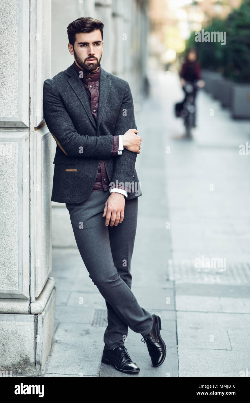 Joven Hombre Barbado, modelo la moda, de pie en el fondo urbano vistiendo traje elegante británico. Chico con barba y peinado moderno la calle Fotografía de stock - Alamy
