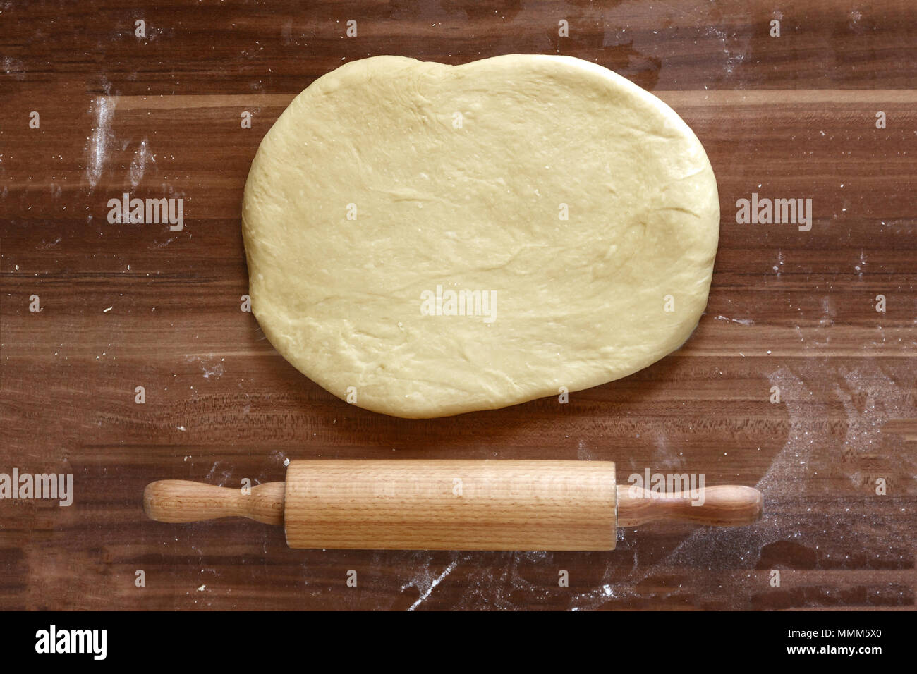 Hacer pizza casera en un país cocina con una vista aérea de desenrollar la  masa en la base con un rodillo de madera sobre papel de horno en una vieja  wo Fotografía