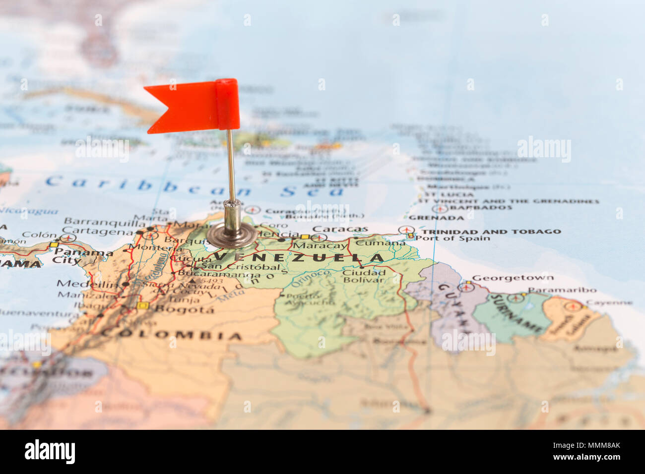 La pequeña bandera roja marcando el país sudamericano de Venezuela en un mapa del mundo. Foto de stock