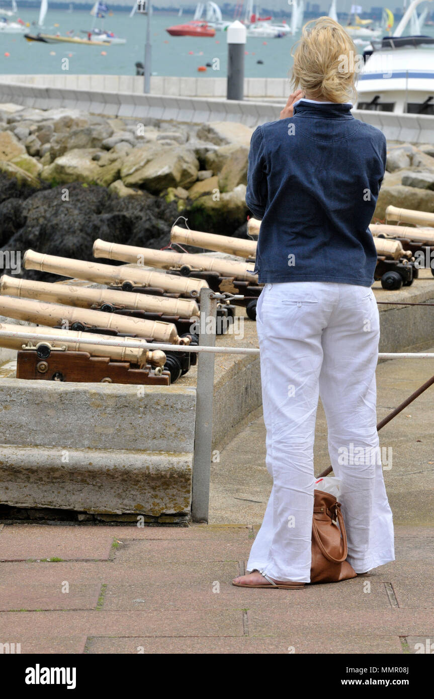 Una mujer vestida de yates y botes de ropa de estilo junto a la Royal Yacht  Squadron empezando los cánones o pistolas durante la semana de Cowes en la  isla de Wight
