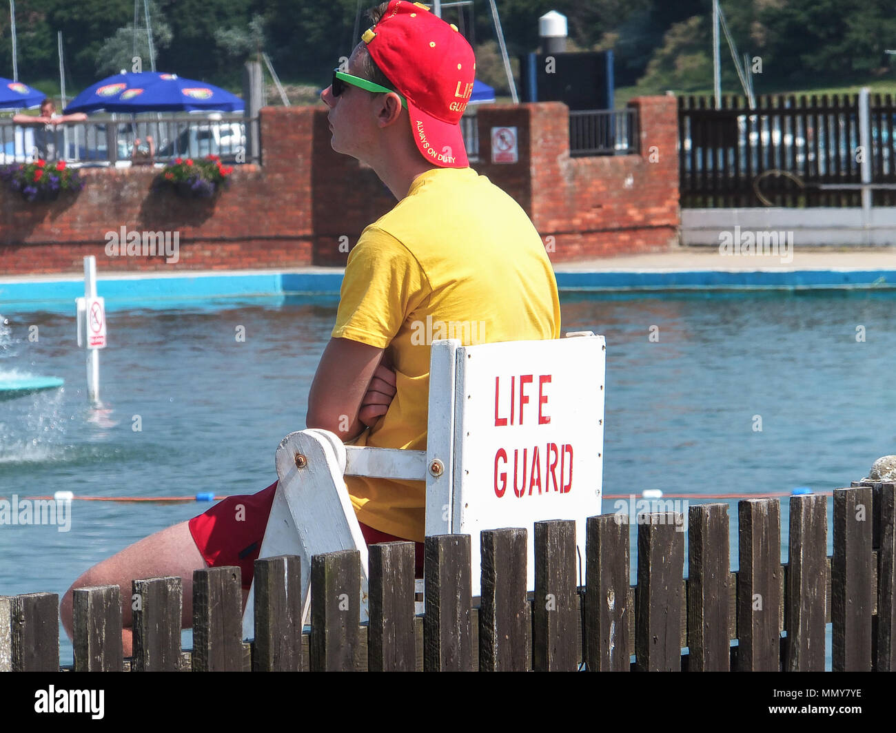 Hombre socorrista en gafas de sol cerca de la piscina pública