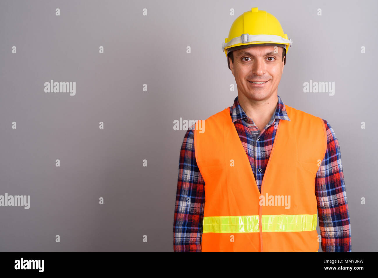 El hombre trabajador de la construcción contra el fondo gris Foto de stock