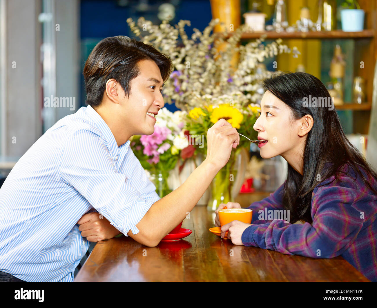 Joven y juguetona amorosa pareja asiática divirtiéndose en la cafetería. Foto de stock