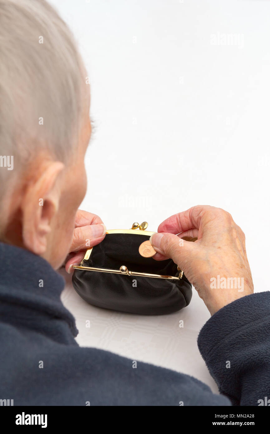 Senior mujer sosteniendo un bolso vacío y una moneda de dos céntimos en sus manos., copia o espacio de texto, la pobreza en la tercera edad concepto Foto de stock
