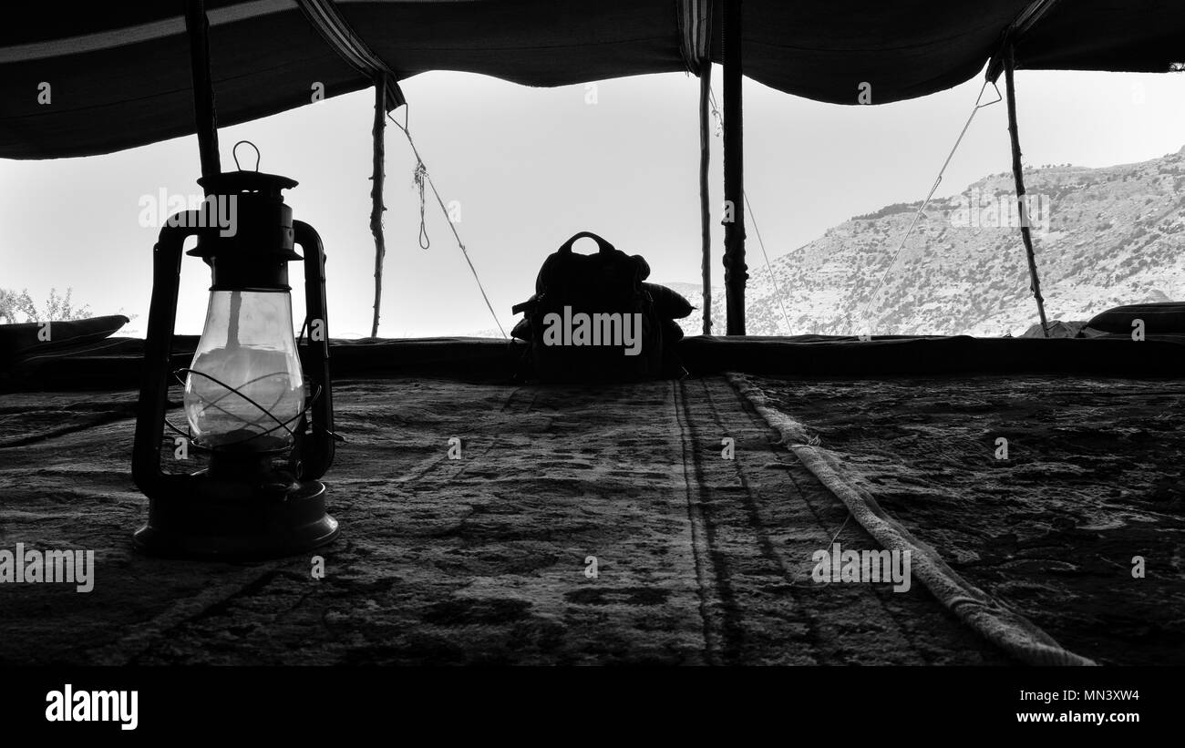 La lámpara del huracán bajo una tienda beduina tradicional con vista sobre un paisaje árido Foto de stock