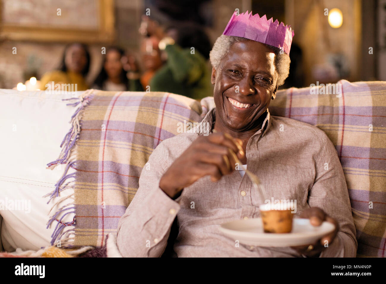 Retrato sonriente, feliz senior hombre vestido con la Navidad de papel corona, disfrutando el postre Foto de stock