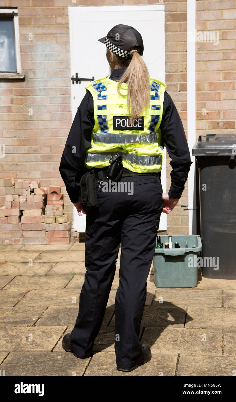 Vista vertical trasero de una mujer policía llevaba una gorra y esperando  por una puerta Fotografía de stock - Alamy