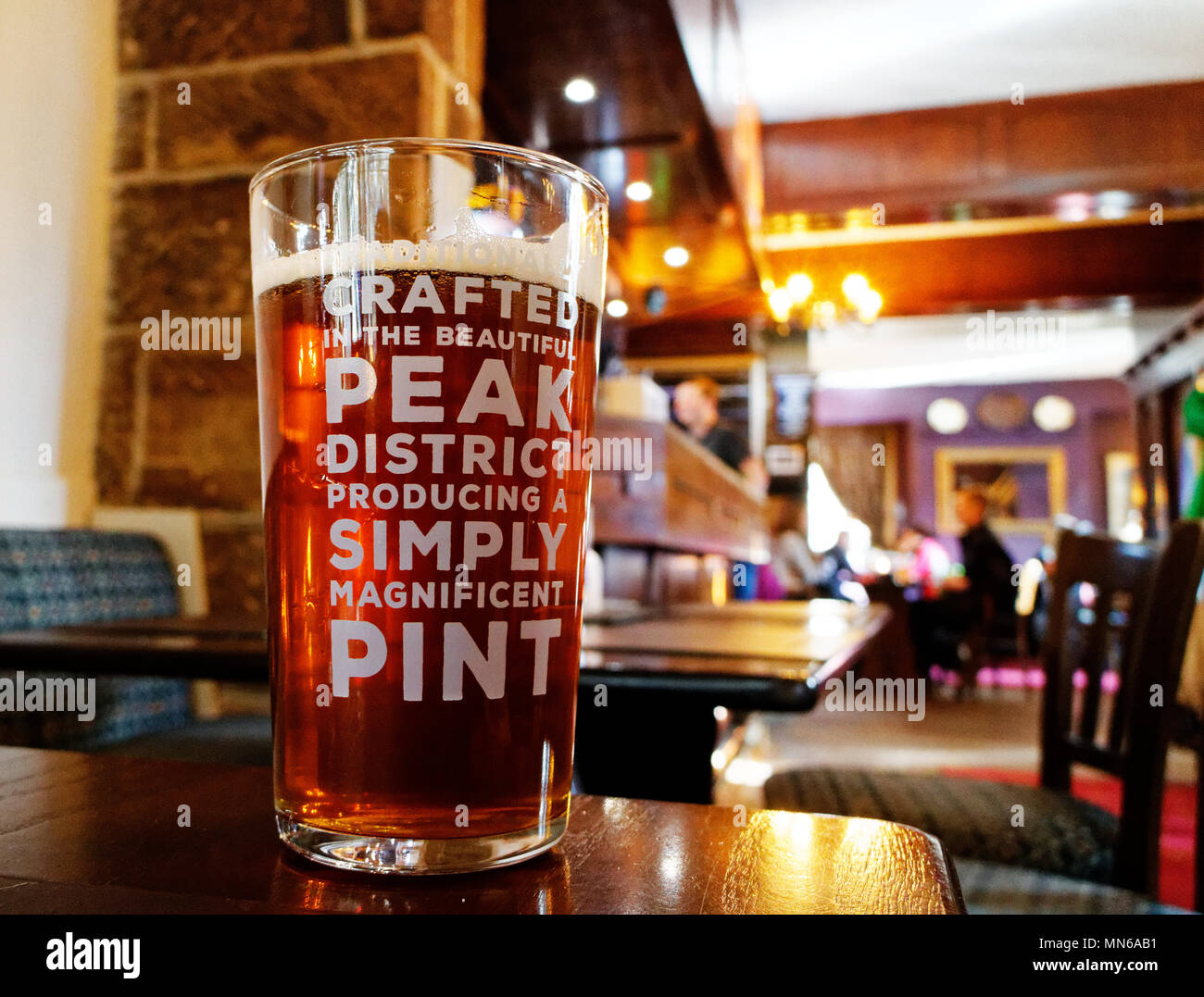 Una pinta de cerveza en una tabla. El pub es el Peacock Inn en Bakewell y la cerveza está fabricada localmente. Foto de stock