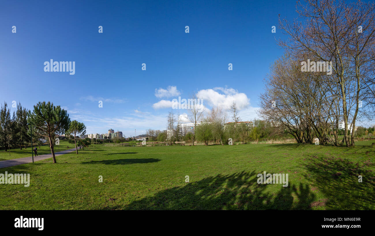 Gran césped verde campo vacío, con las vistas de la ciudad en el Parque da Devesa Parque Urbano. Blue Sky, grandes nubes blancas. Vila Nova de Famalicao, Portugal Foto de stock