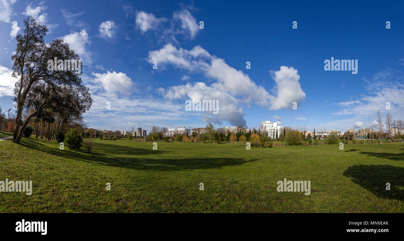 Gran césped verde campo vacío, con las vistas de la ciudad en el Parque da Devesa Parque Urbano. Blue Sky, grandes nubes blancas. Vila Nova de Famalicao, Portugal Foto de stock