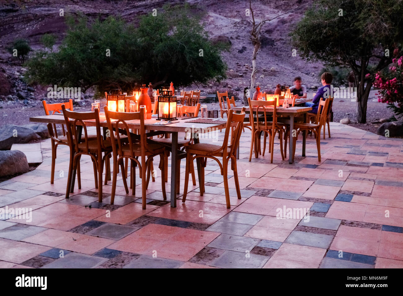 Zona de estar exterior del restaurante iluminado por velas en un paisaje seco Foto de stock