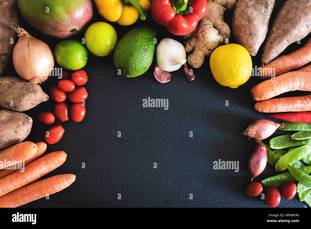 Directamente encima de acercamiento de verduras y frutas frescas orgánicas sobre pizarra cocina Foto de stock
