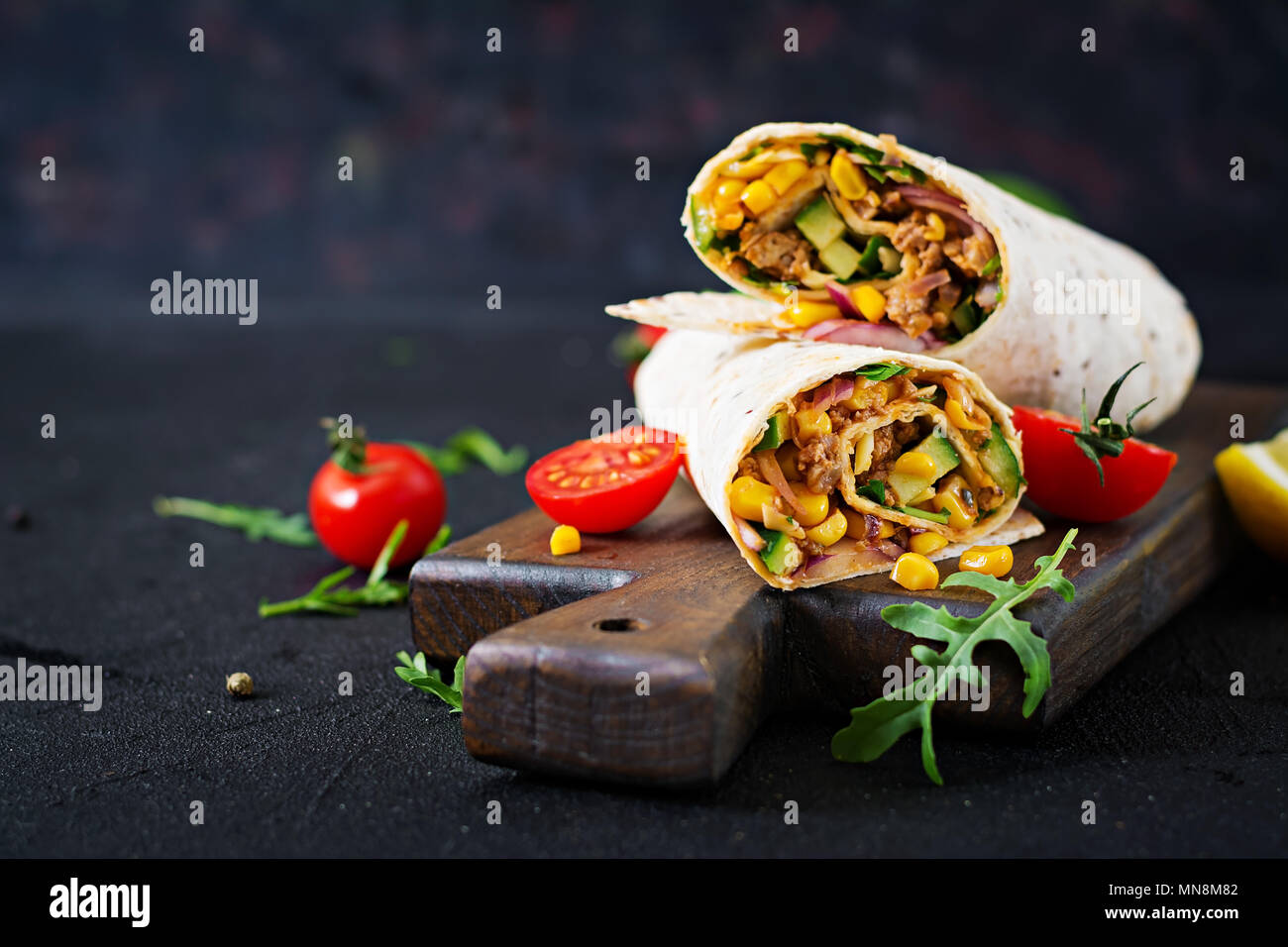 Los burritos se envuelve con la carne y verduras sobre fondo negro