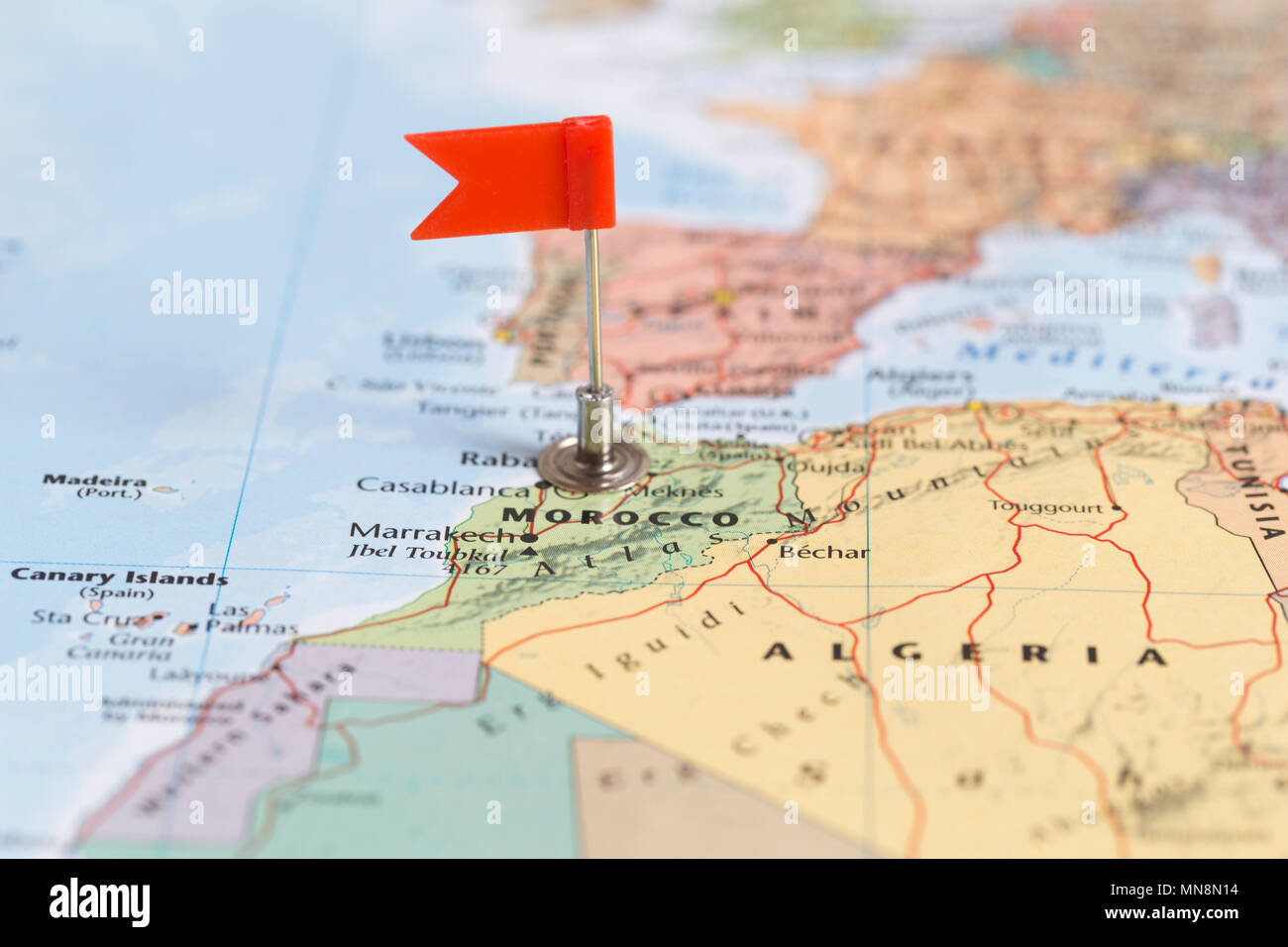 La pequeña bandera roja marcando el país africano de Marruecos en un mapa del mundo. Foto de stock