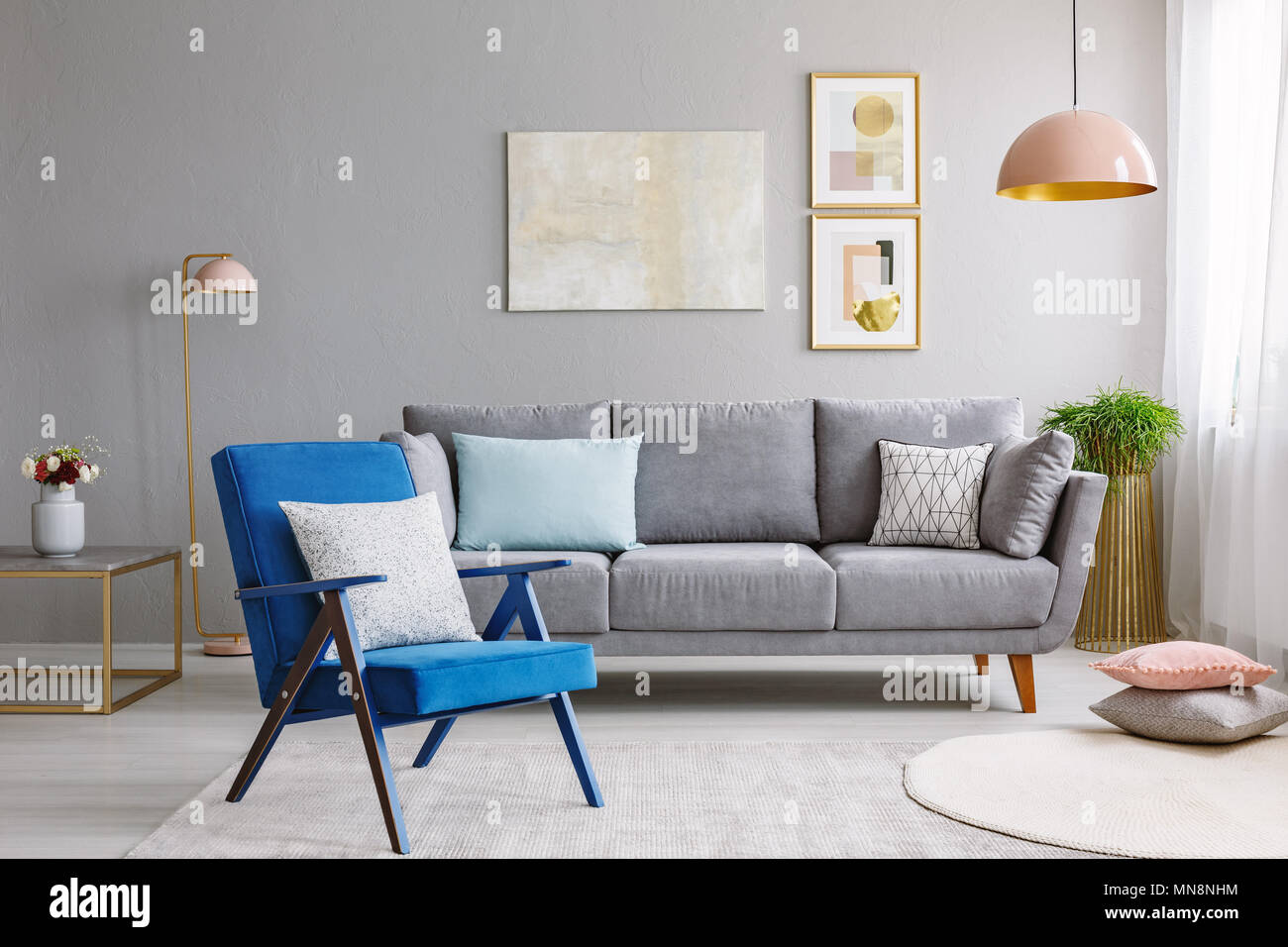 Sillón azul cerca del sofá gris en la moderna sala interior con poster y  Rosa Luz. Foto real Fotografía de stock - Alamy