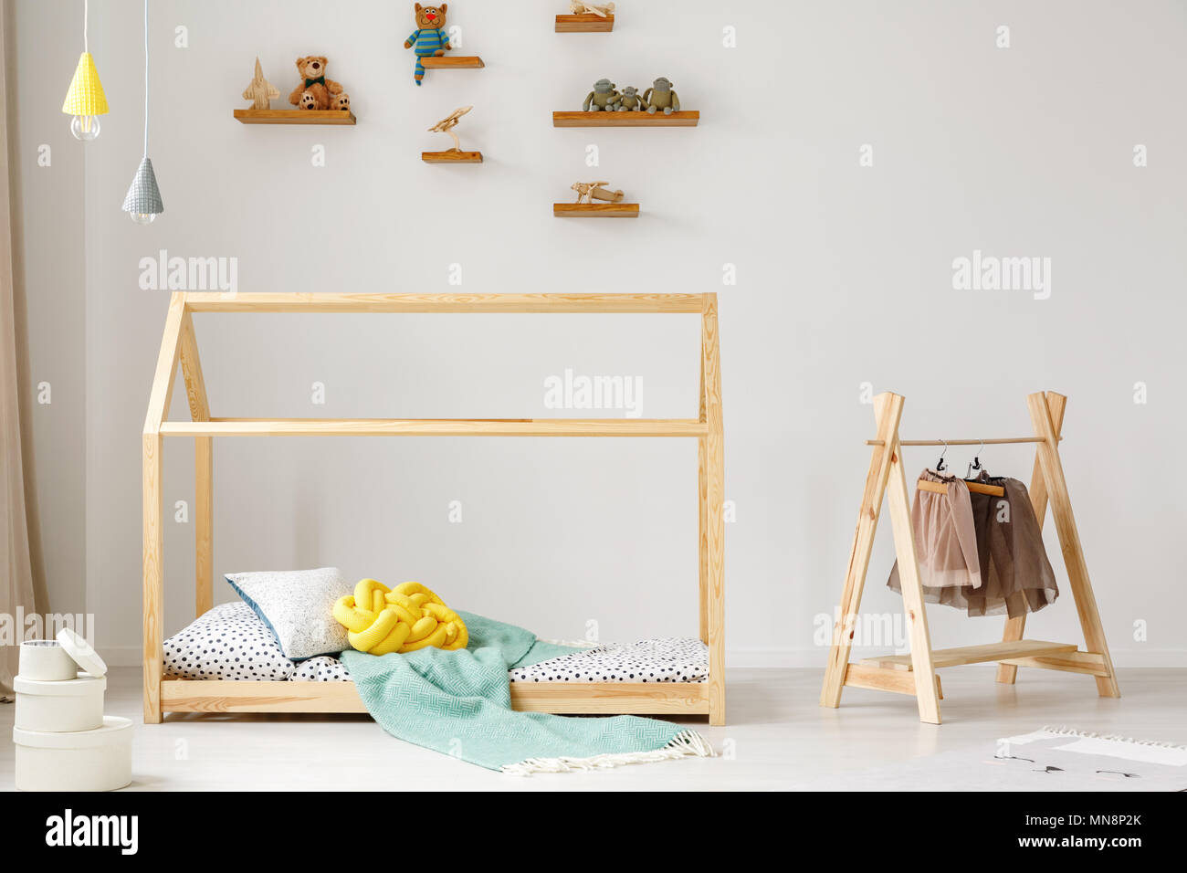 Ropa en un rack junto a una cama de madera en DIY dormitorio infantil  interior con lámparas de helados Fotografía de stock - Alamy