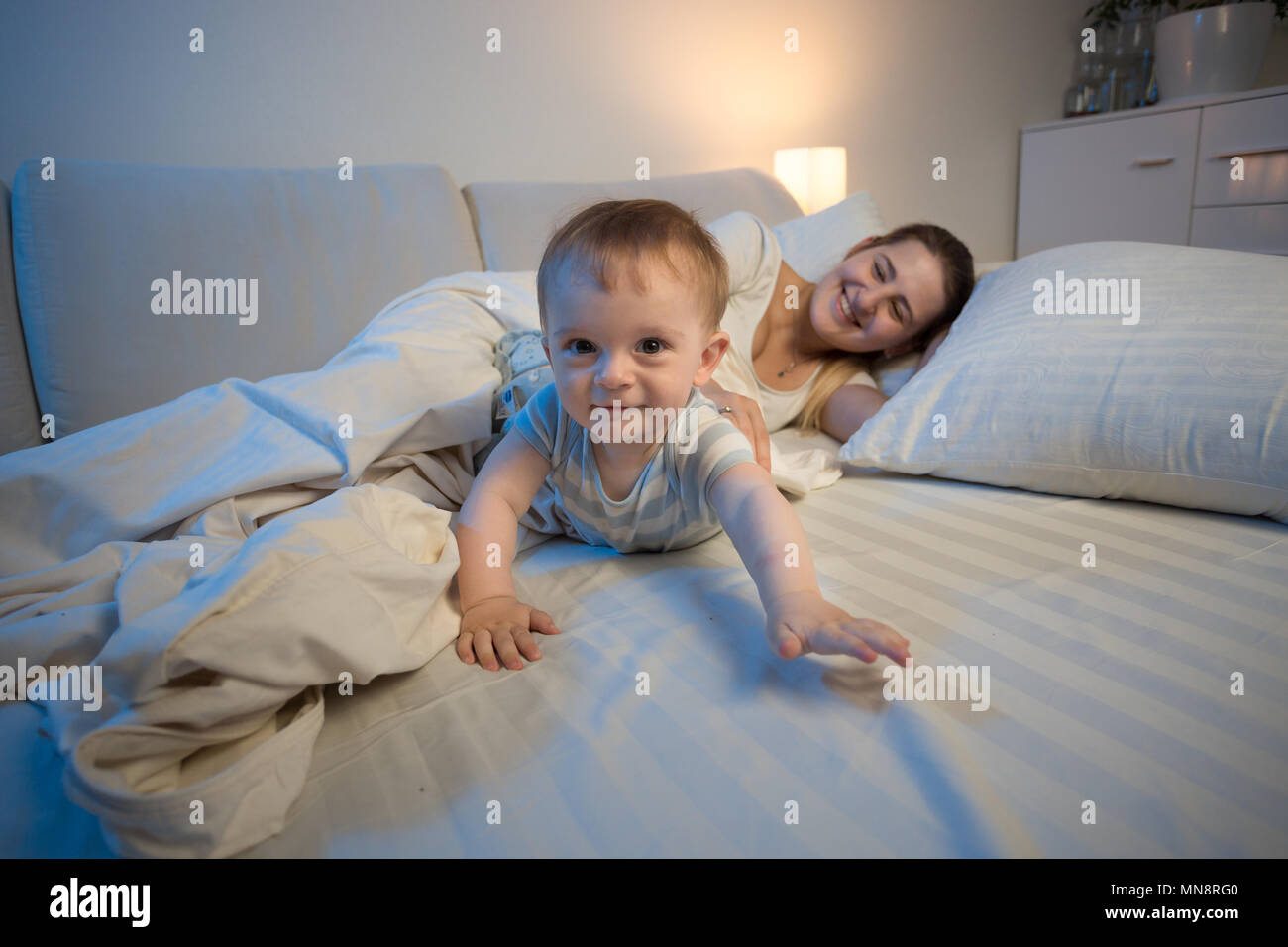 Cute smiling Baby Boy arrastrándose sobre la cama hacia la cámara Foto de stock