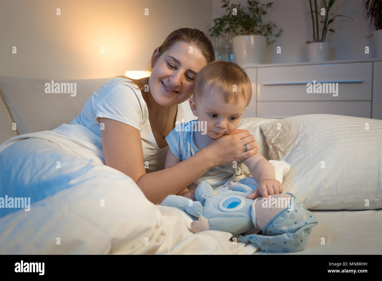 Sonriente joven madre abrazando a su hijo antes de ir a dormir? Foto de stock