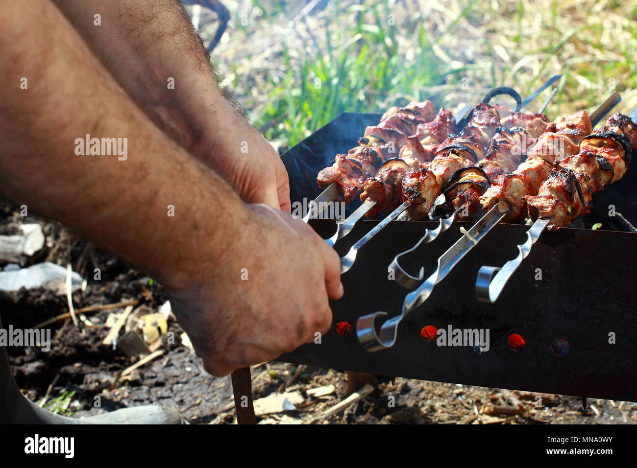 Un hombre se prepara a la parrilla delicioso asado. Foto de stock