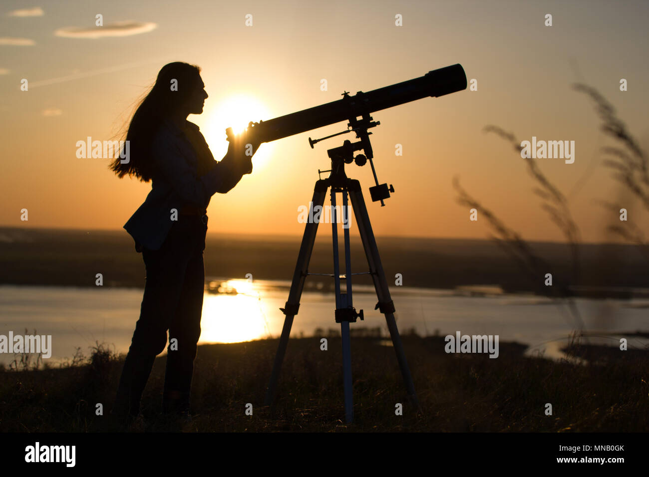 Silueta de mujer joven mirando a través del telescopio vista al
