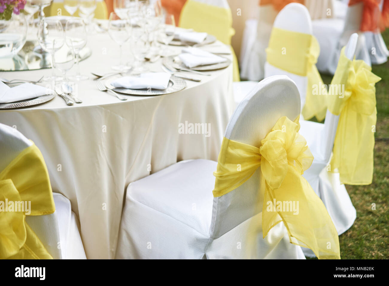 La recepción de la boda mesa con sillas de cubierta blanca de spandex con guillotina de organza amarillo Foto de stock