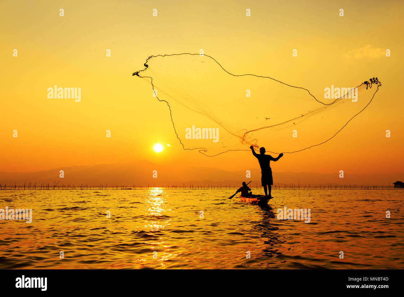 Tirar la red de pesca durante la puesta de sol Fotografía de stock - Alamy