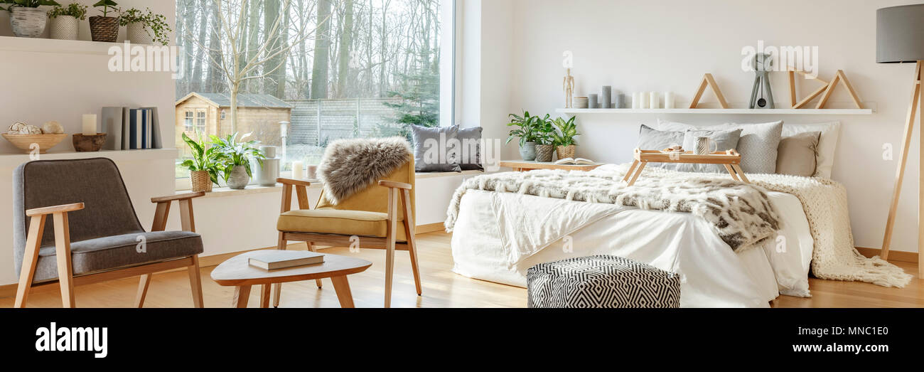 Foto real de un dormitorio multifuncional interior con sillones retro junto  a una cama blanca con quillango y bandeja de madera Fotografía de stock -  Alamy