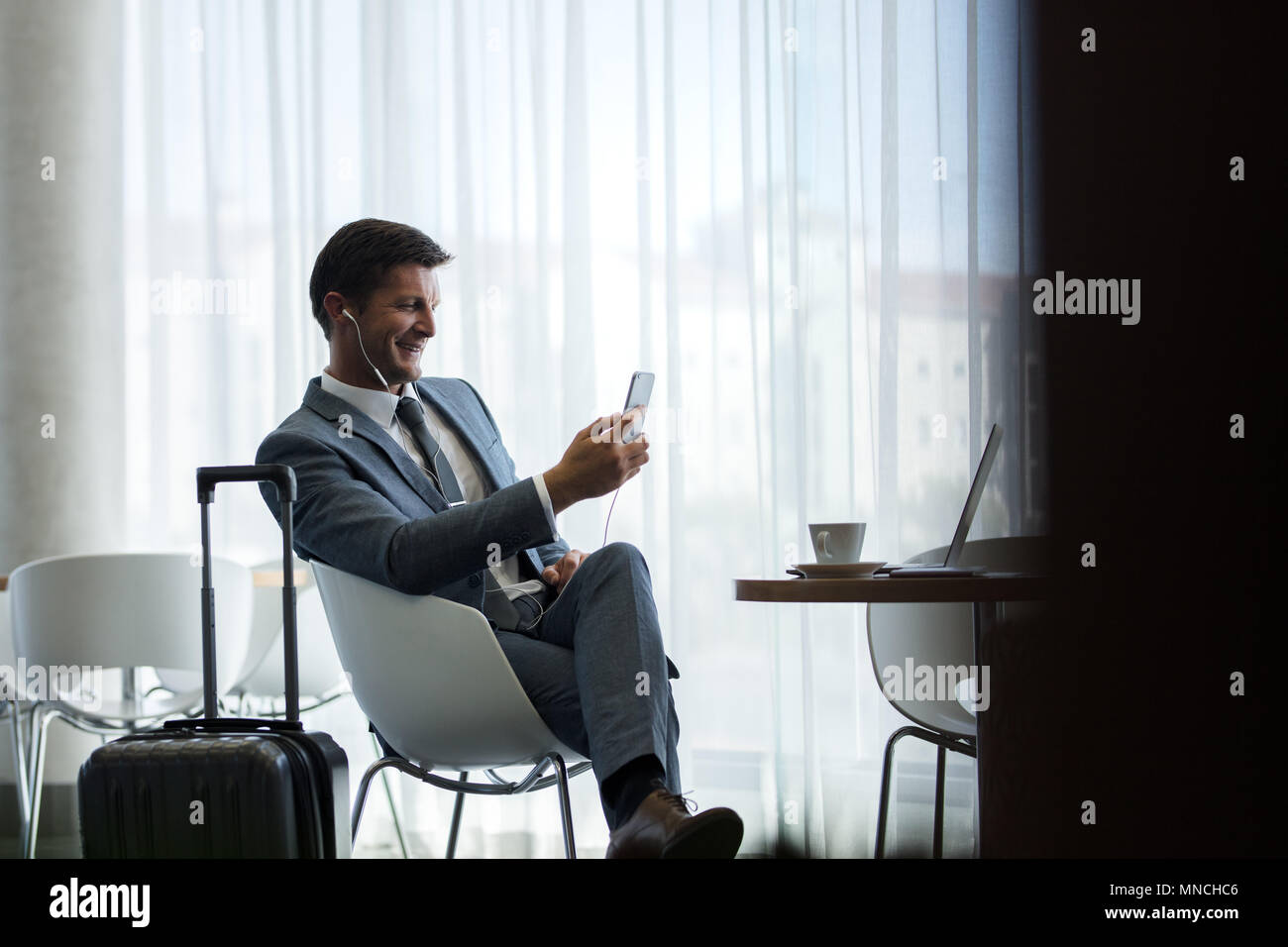 Empresario ir en un viaje de negocios a la espera en el aeropuerto para su vuelo y hacer video llamada desde su teléfono móvil. Foto de stock
