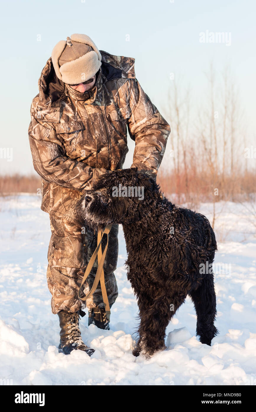 Riesenschnauzer negro perro con su maestro en un paseo en invierno día de nieve Foto de stock