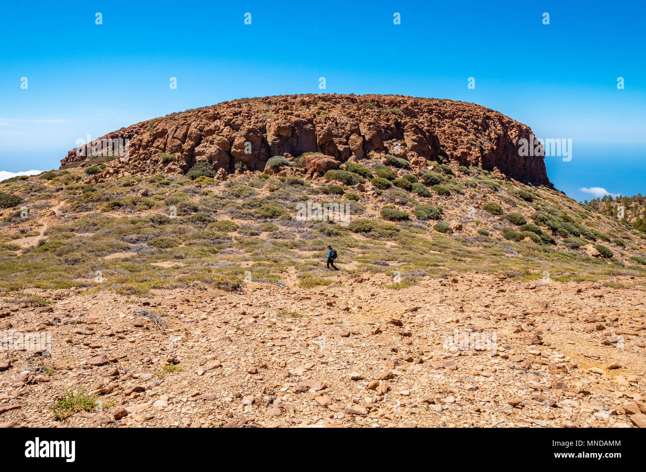 Un caminante solitario debajo de la meseta abovedada de sombrero de Chasna un tapón de basalto en la caldera del volcán el Teide en Tenerife, Islas Canarias Foto de stock