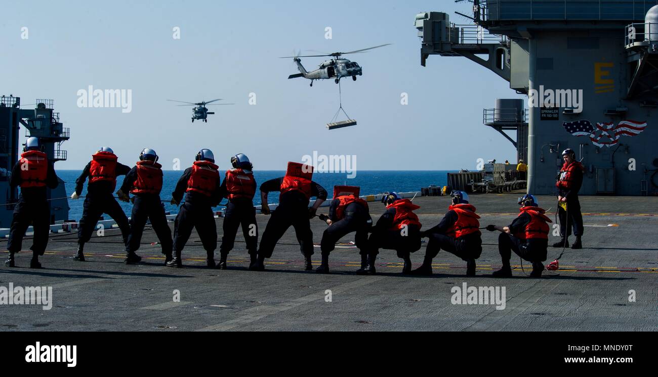 180515-N-OY799-0290 las aguas al sur de Japón (15 de mayo de 2018) Los marineros de cubierta departamento hombre el teléfono y distancia en línea de la cubierta de vuelo como MH-60S mar, halcones, asignado al comando de Transporte Marítimo Militar (MSC) carga seca/municiones buque USNS César Chávez (T-AKE 14), entregar explosivos a la Marina desplegadas, el portaviones USS Ronald Reagan (CVN 76), como parte de una reposición en alta mar durante las pruebas de mar, 15 de mayo de 2018. Los civiles no combatientes, con tripulación de barco, operado por la MSC, proporciona el combustible, alimentos, municiones, piezas de repuesto, el correo y otros suministros a los buques de la Marina en todo el mundo. Ronald Reagan, el f Foto de stock