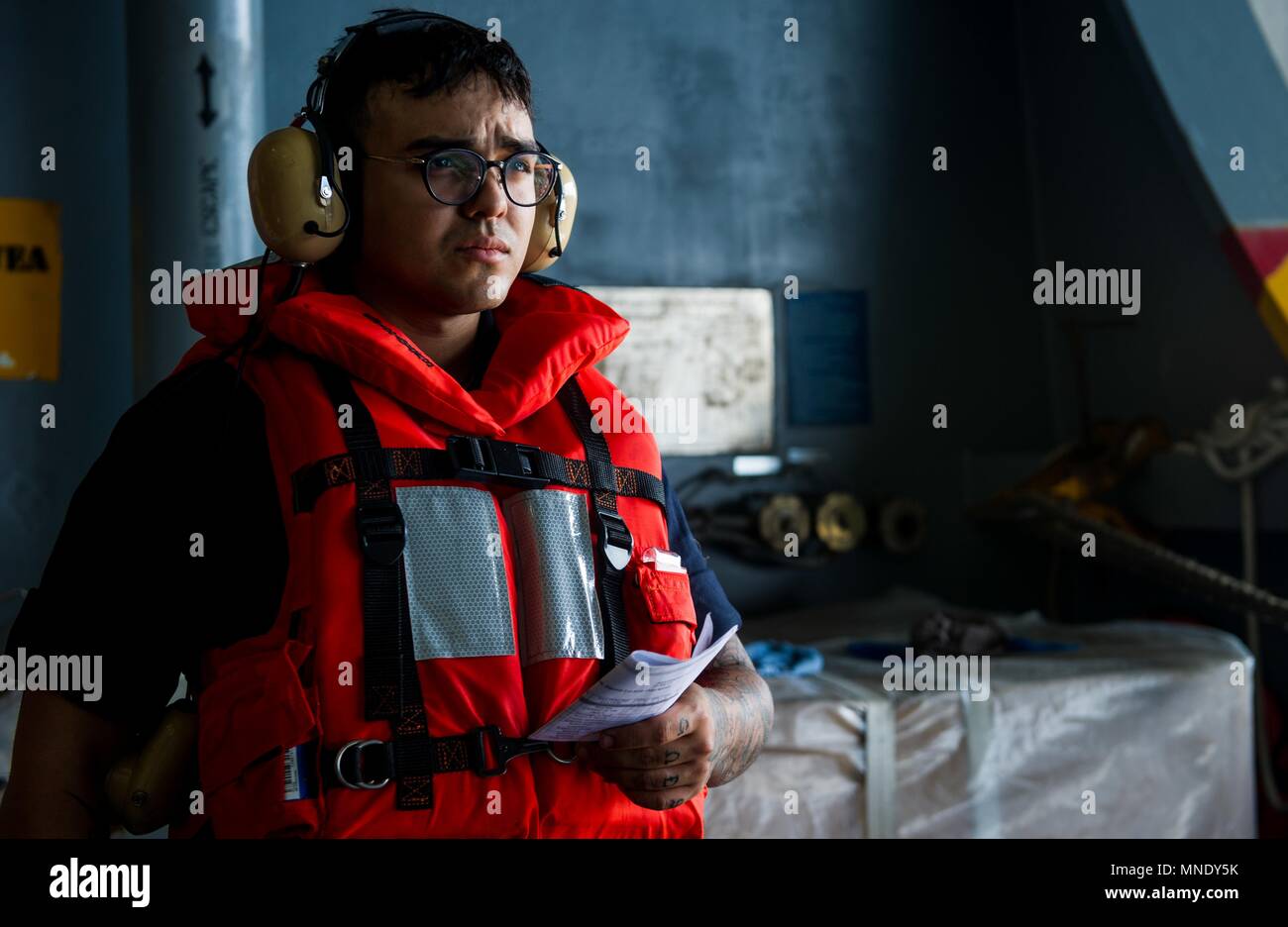 180515-N-OY799-0210 las aguas al sur de Japón (15 de mayo de 2018) Boatswain's Mate Seaman Yoshua Núñez, de Orlando, Florida, mans un sonido-powered teléfono en el hangar bay a bordo de la Marina desplegadas, el portaviones USS Ronald Reagan (CVN 76), como parte de una reposición en alta mar con el comando de Transporte Marítimo Militar (MSC) carga seca/municiones buque USNS César Chávez (T-AKE 14), durante las pruebas de mar, 15 de mayo de 2018. Los civiles no combatientes, con tripulación de barco, operado por la MSC, proporciona el combustible, alimentos, municiones, piezas de repuesto, el correo y otros suministros a los buques de la Marina en todo el mundo. Ronald Reagan, el buque insignia de Foto de stock