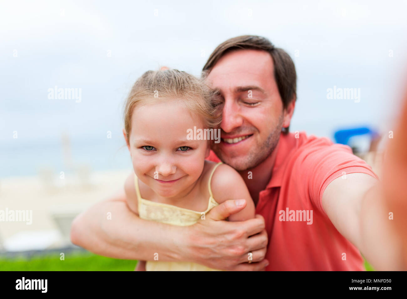 Padre de familia feliz y su adorable hija pequeña en la playa tomando selfie Foto de stock