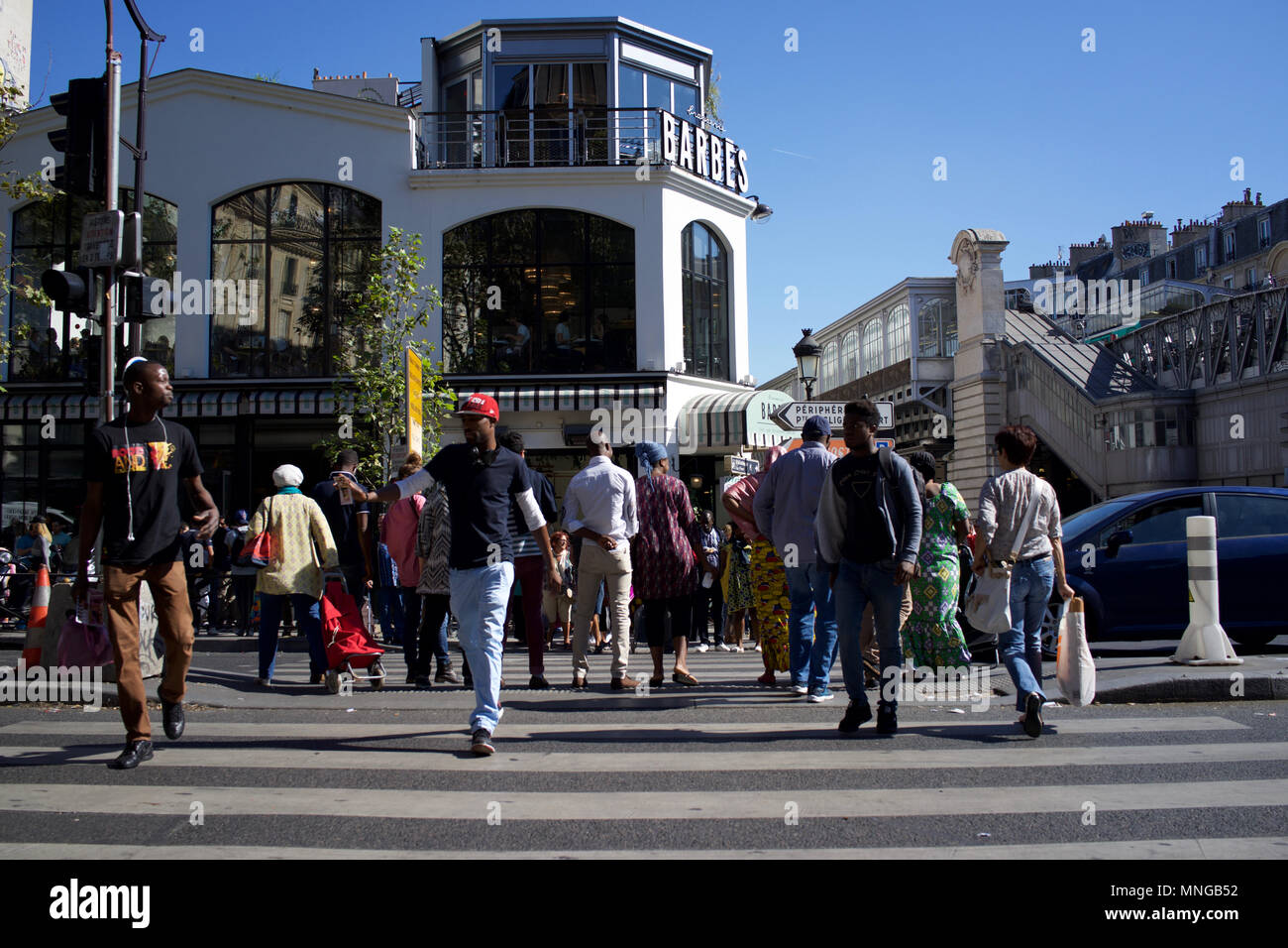 Un concurrido Boulevard Barbès, París, Francia, con Brasserie Barbes en segundo plano - personas cruzando la carretera Foto de stock